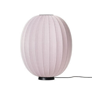 Oval lampe med strikket overflade i lys pink, placeret på en sort base.